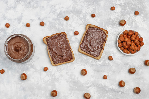 Chocolate spread or nougat cream with hazelnuts in glass jar on